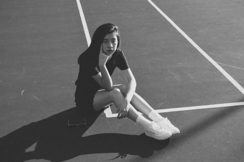a black and white po of a woman sitting on a tennis court