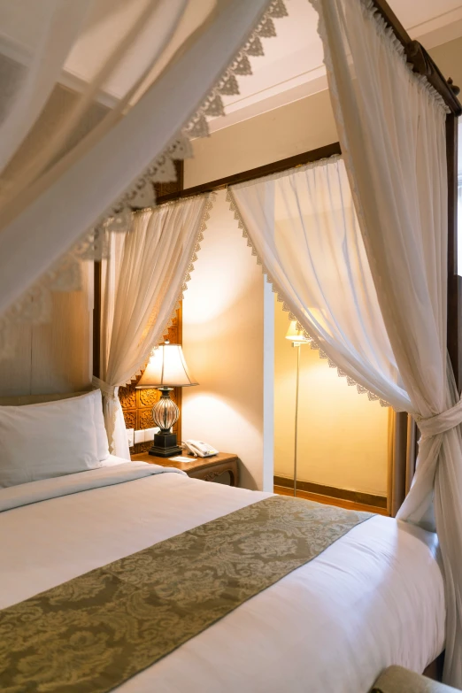 a bed in a bedroom covered with white curtains