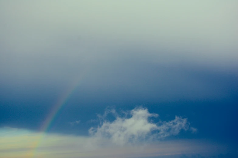 a rainbow is visible on the sky over some clouds