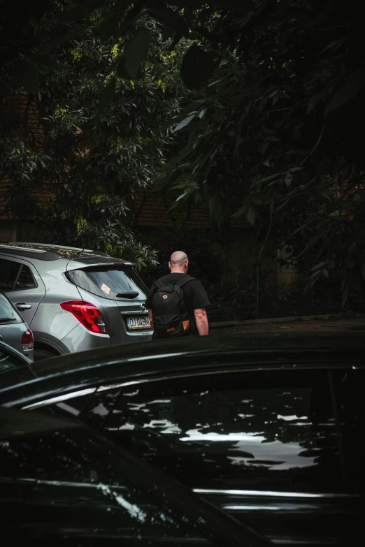 two men are talking while standing next to parked cars