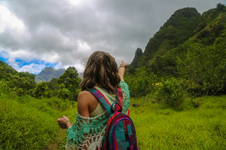 a woman in a dress with a large backpack and backpack on her back looking at the mountain side