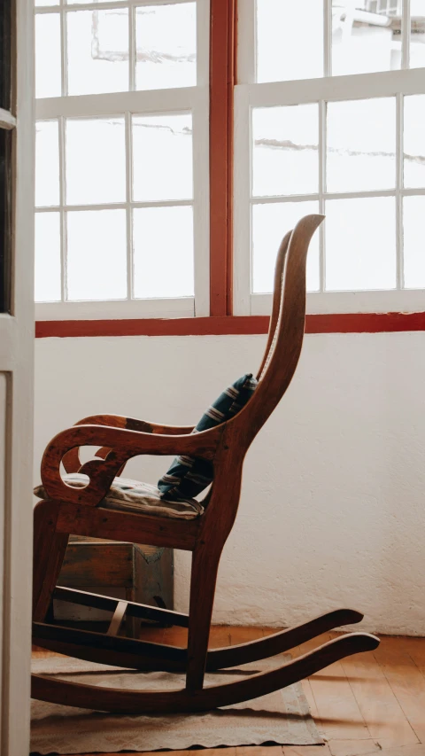 the rocking chair is next to two large windows