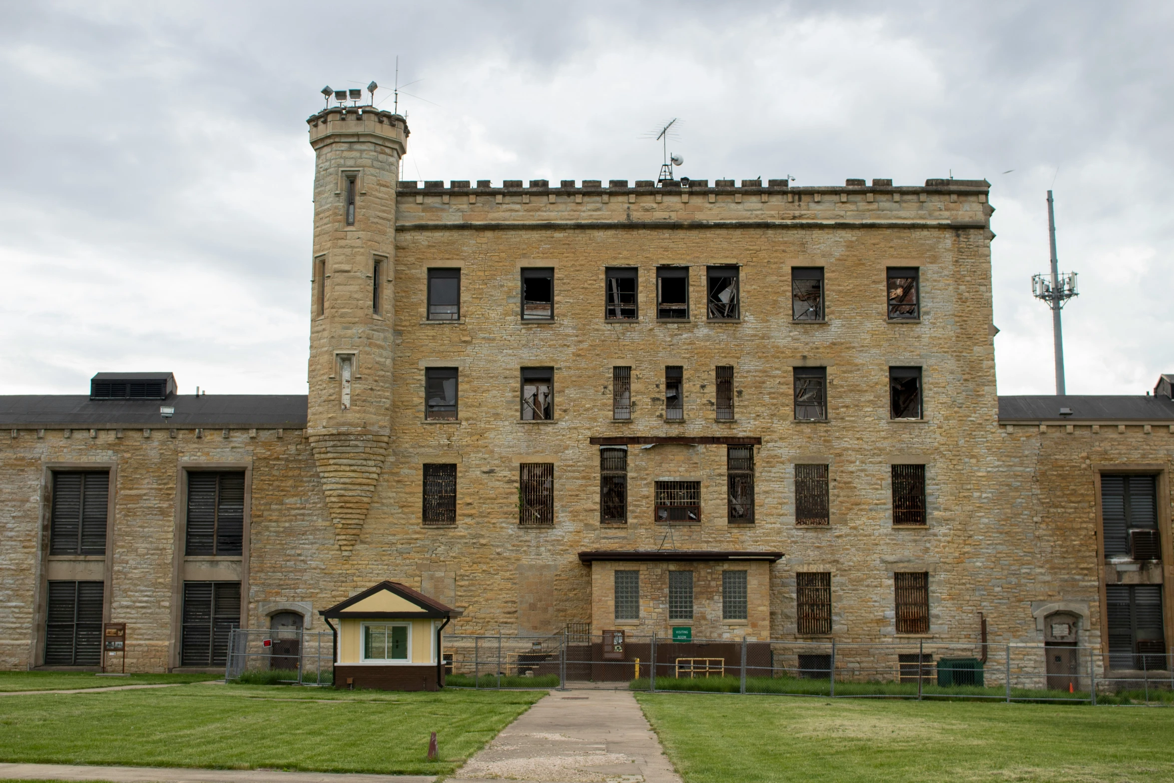 an abandoned brick building with two stories, in front of a field