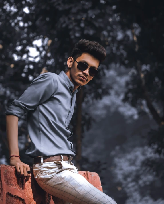 man in sunglasses leaning against the edge of a wall