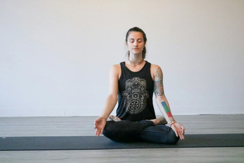 a woman practices a yoga position while sitting on a mat