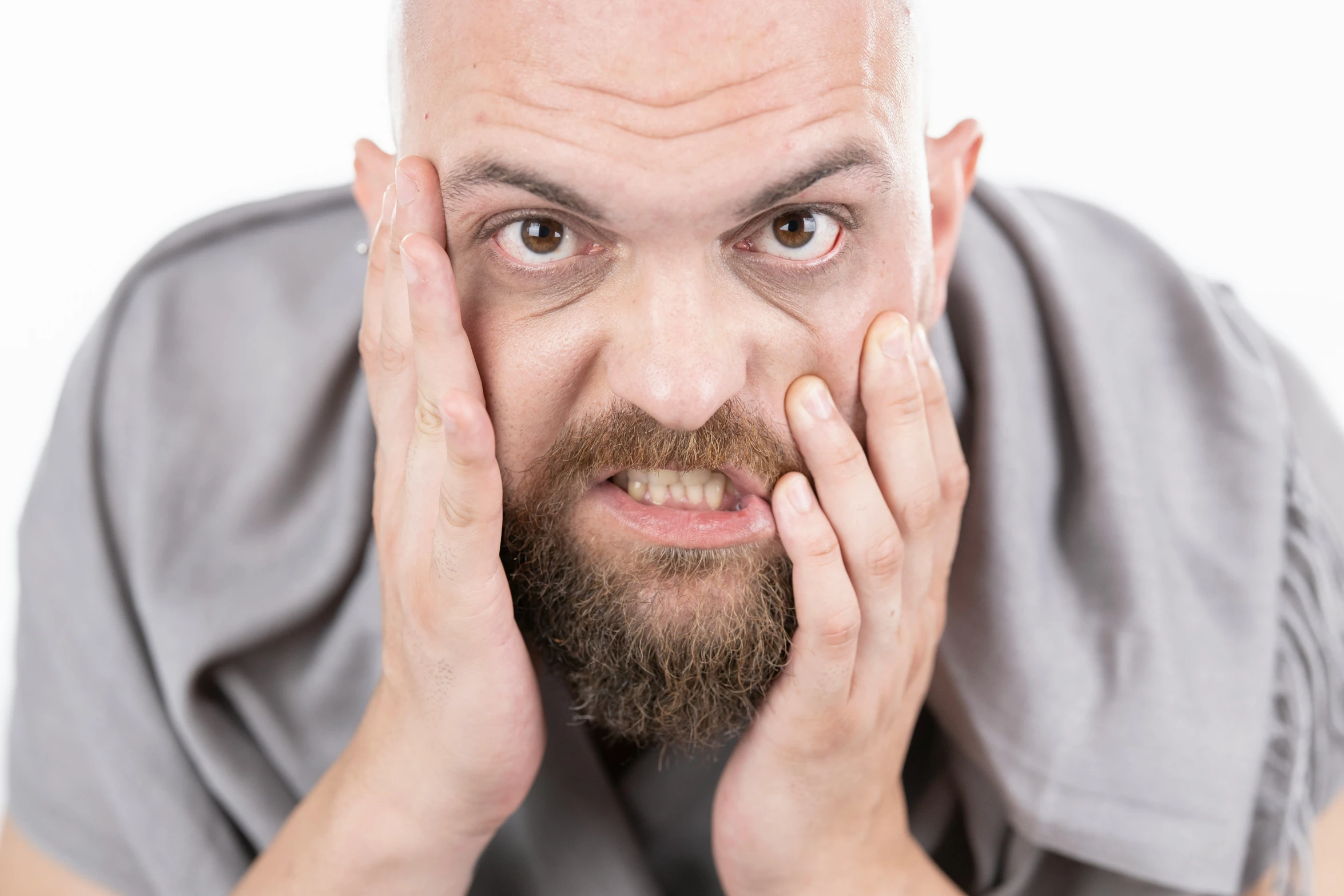 man holding his hand to his face with a frown on it