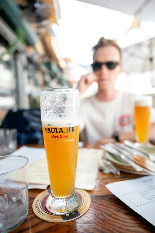 a woman in sunglasses sitting next to glasses of beer