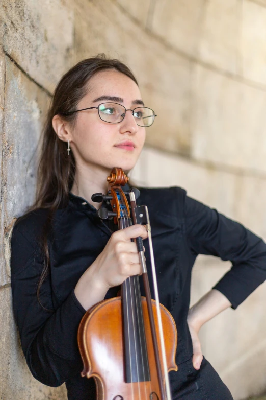 a young woman is playing violin on the street