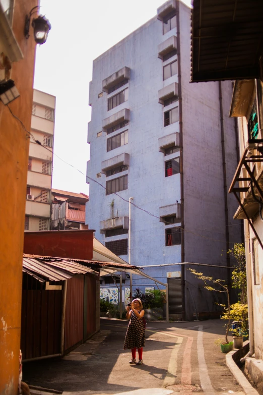 a woman walks down an empty street between two buildings