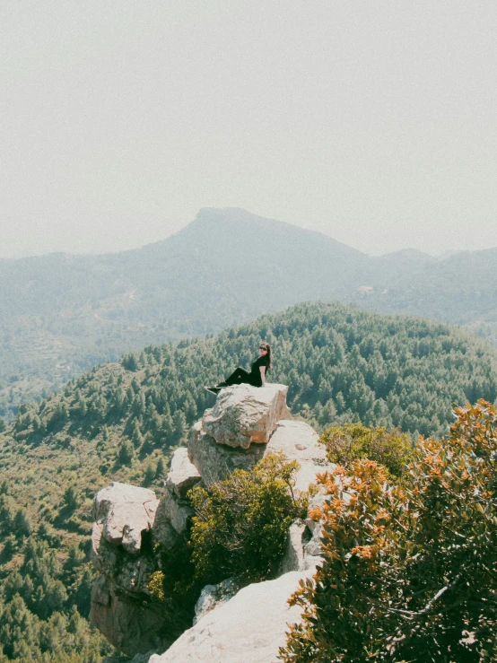 a woman sits on the edge of a cliff