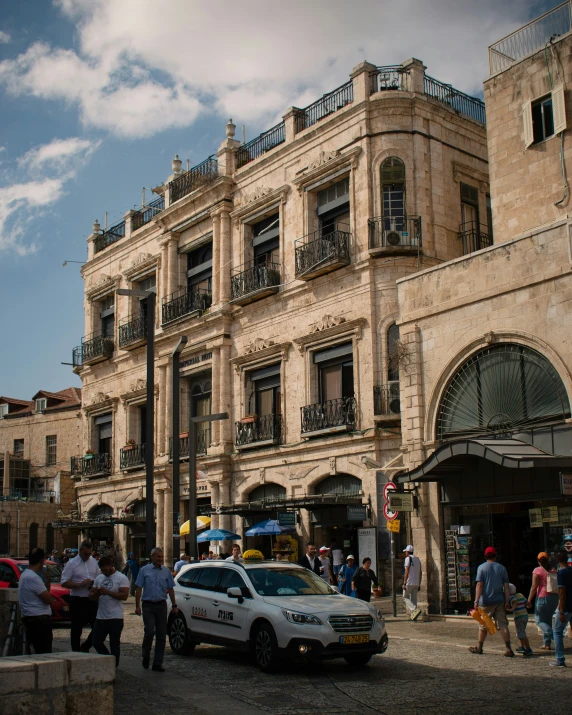 several people walk around a parking area near an old building