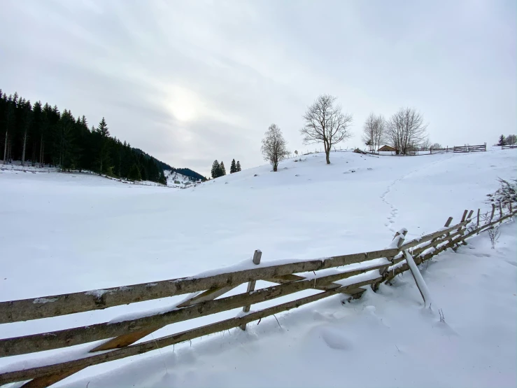 a fence is covered with fresh snow by a hill