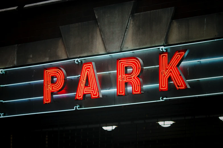 a bright, lit neon sign displays the name of a city park