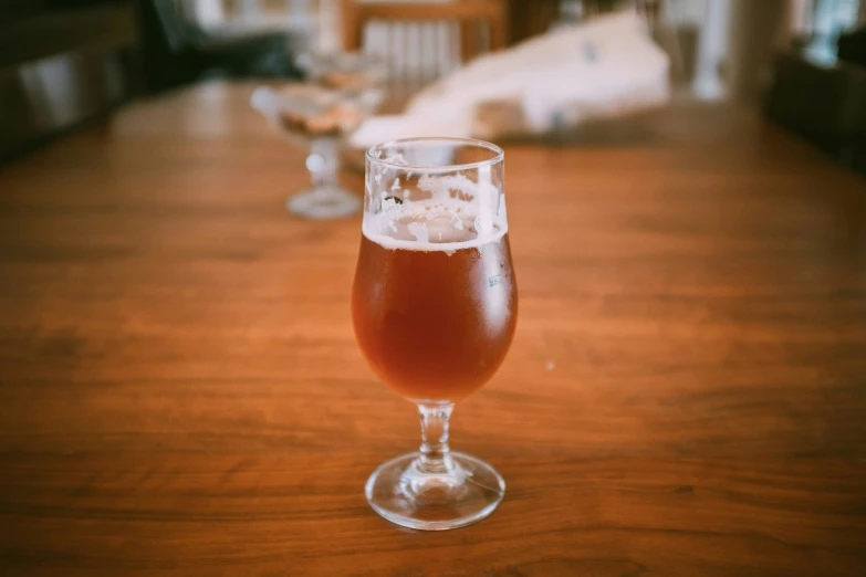 a glass of liquid sitting on top of a wooden table