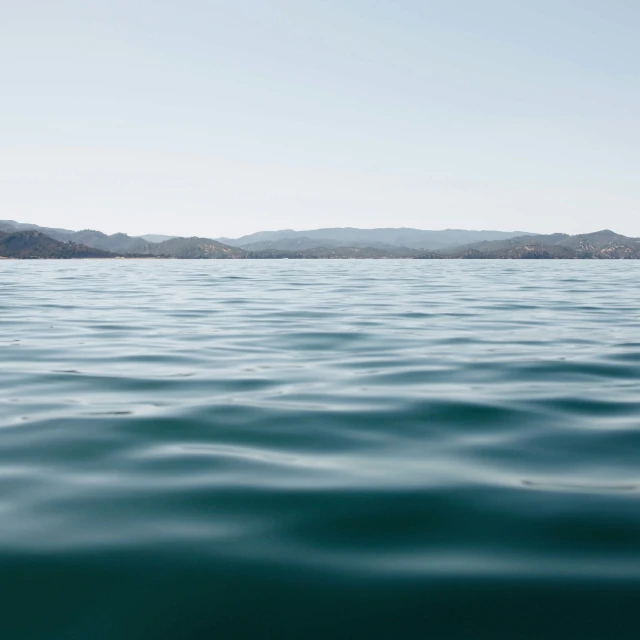 the water with the mountain in the distance is blue