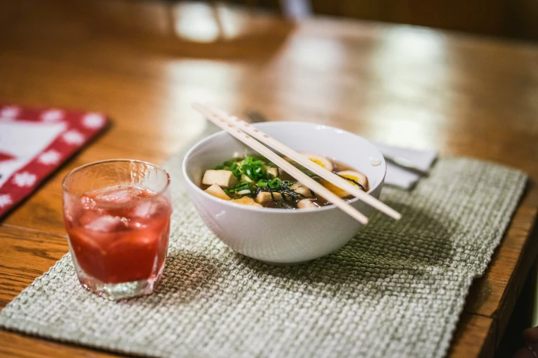 a bowl with chopsticks is placed next to a drink