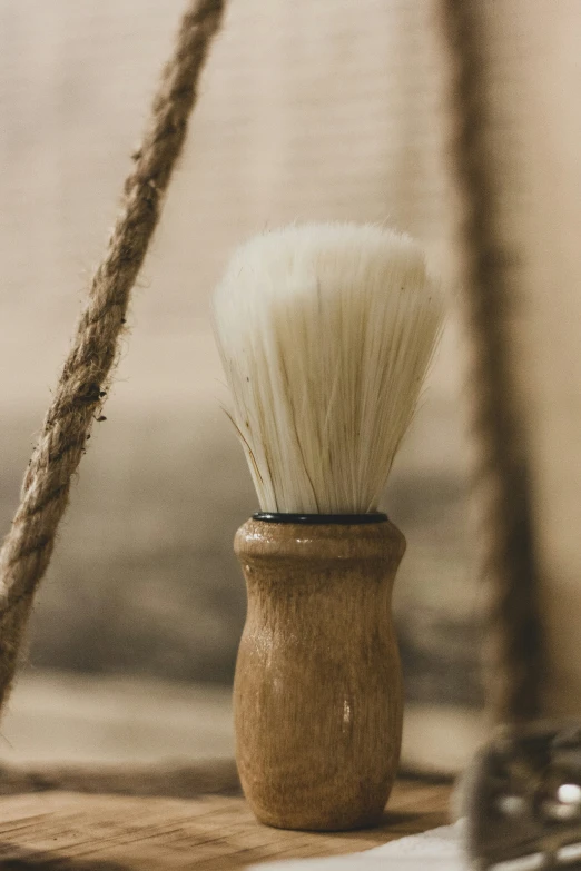 a white shaving brush sits on a wooden stand