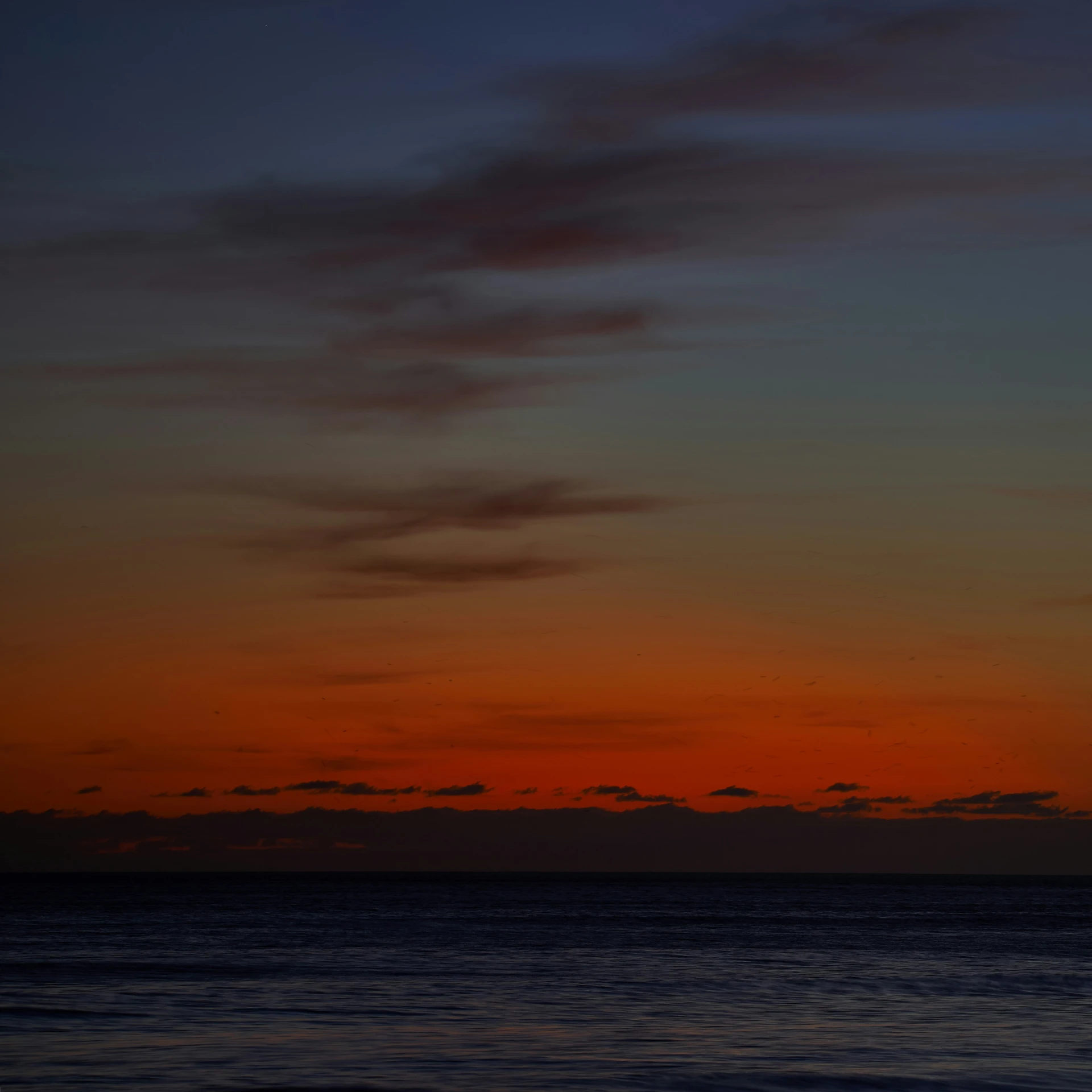 the sun sets over the ocean with a boat on it