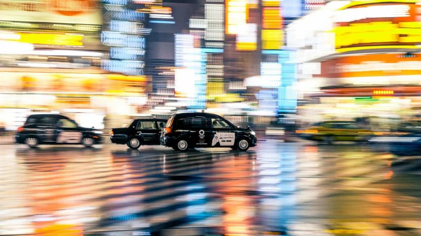 a black car is driving down the street in the city