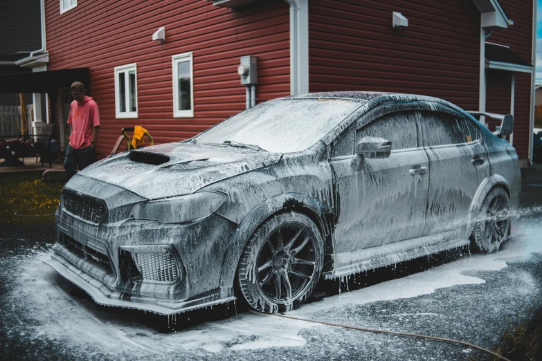 a car covered in ice and snow while a man looks at it