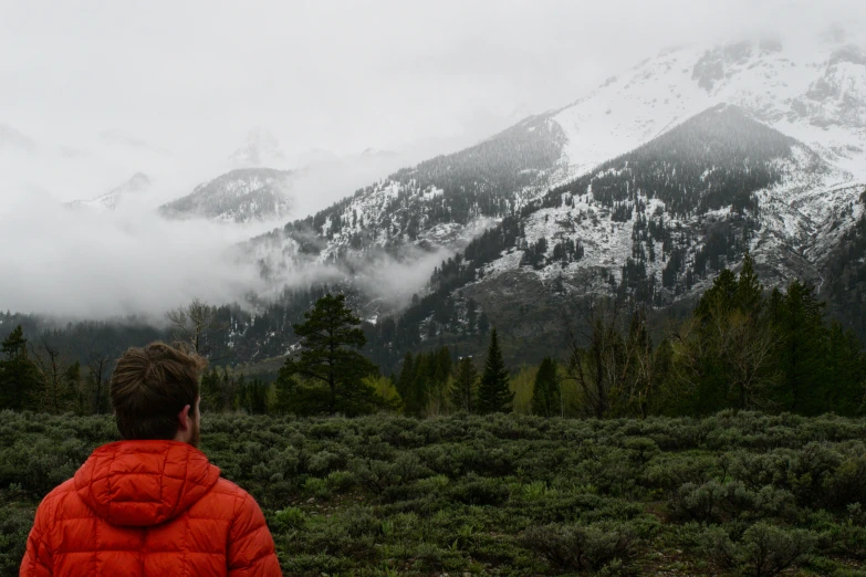 a young man is standing near a mountain