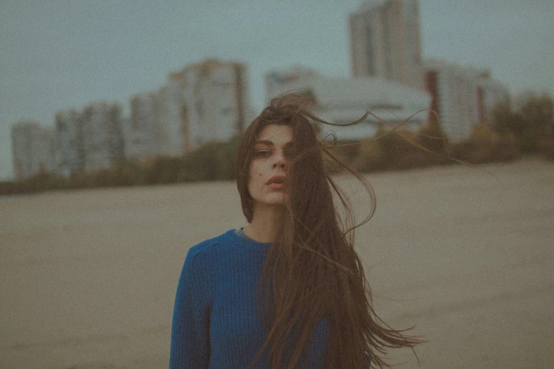 a woman with long hair standing on top of the beach