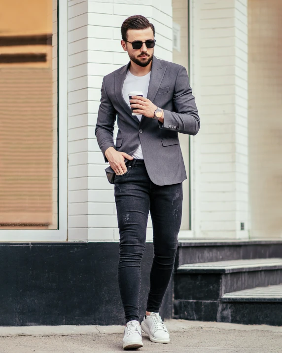 a man is standing on a street with sunglasses and holding a cell phone