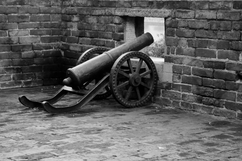 there is an old cannon on the ground next to a brick wall