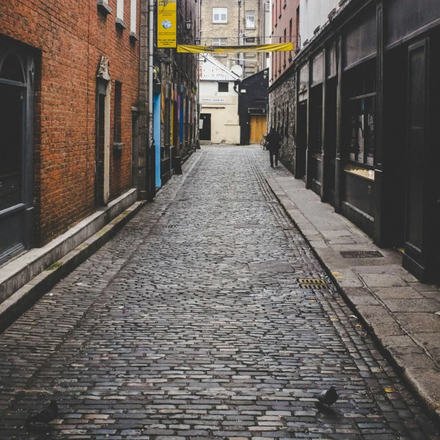 a dark cobbled street is next to an old brick building