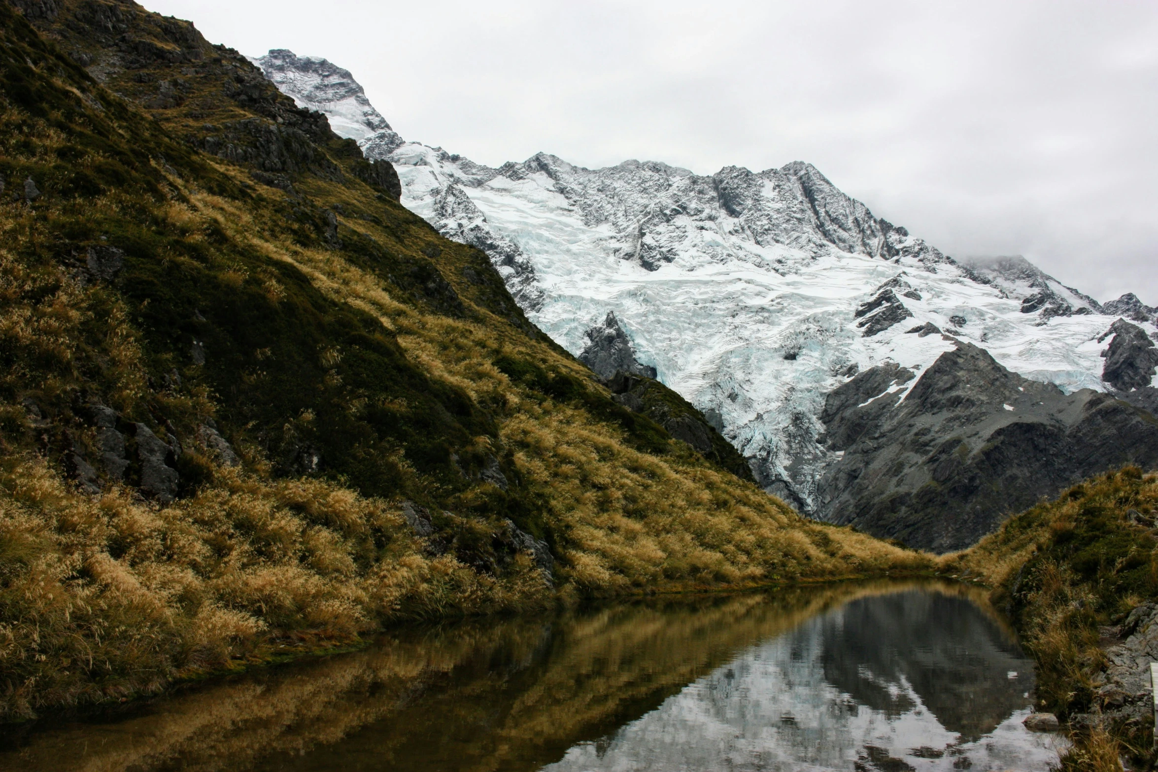 a mountain covered in lots of snow sitting above a lake