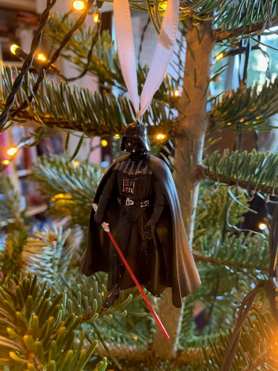 a star wars themed ornament hangs from a christmas tree