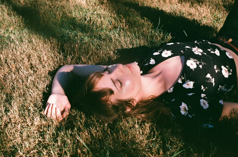 the woman is lying on the grass in a flowered dress