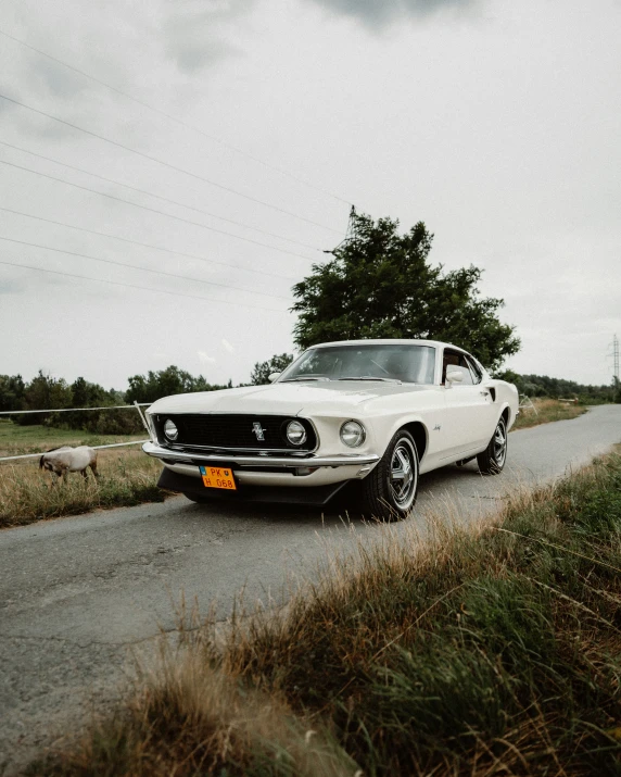 an old mustang car is parked on the side of a road near a field