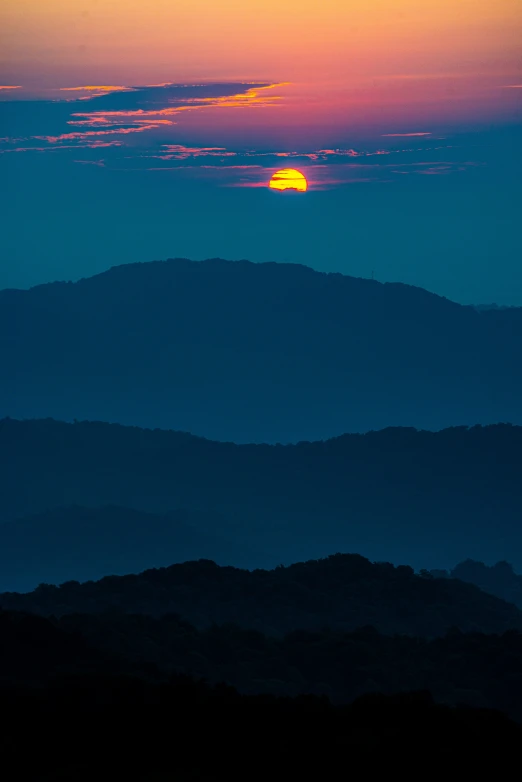 the sun is setting over the mountains on the horizon