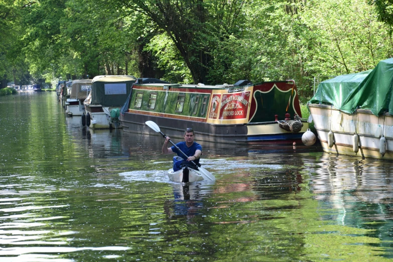 a person paddles through the water by a boat