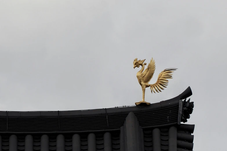 the golden bird sculpture atop the roof is perched on top of a building