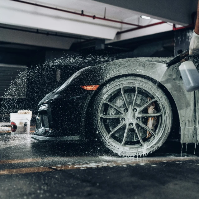 a man is washing a sports car with foam