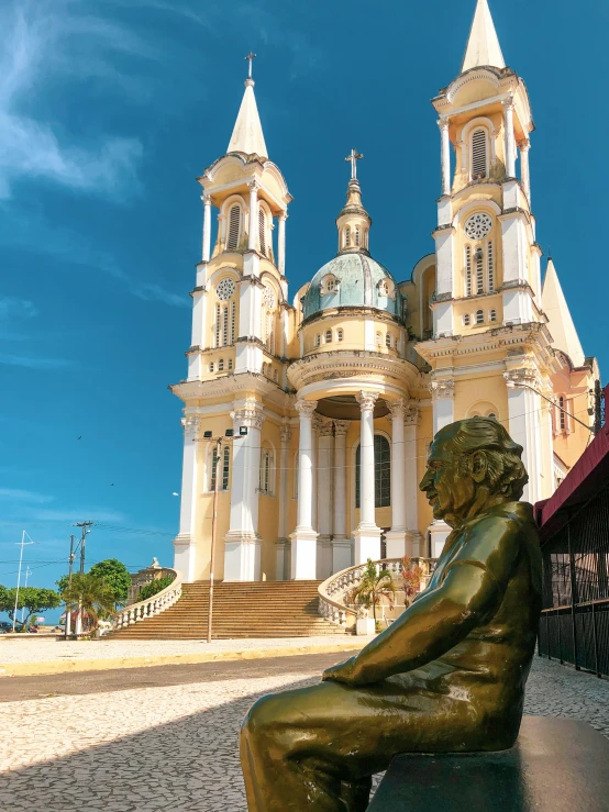 a statue sits on top of a stone platform outside of a large building