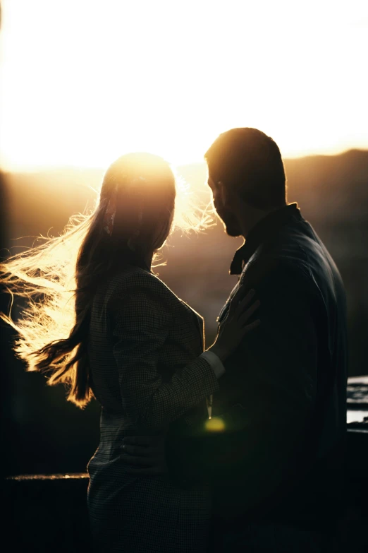 a man and woman at sunset holding each other's hands