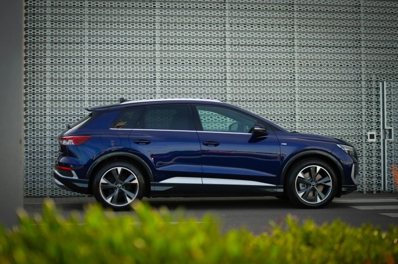 an audi cayen blue suv parked next to a gray wall