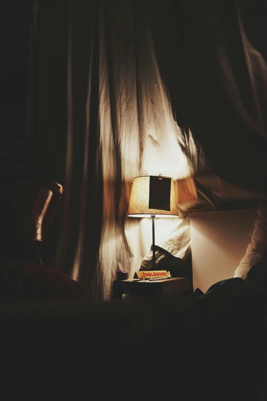 a lamp next to a bed in a dimly lit room