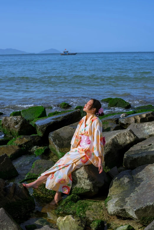 woman sitting on the rocks next to the water