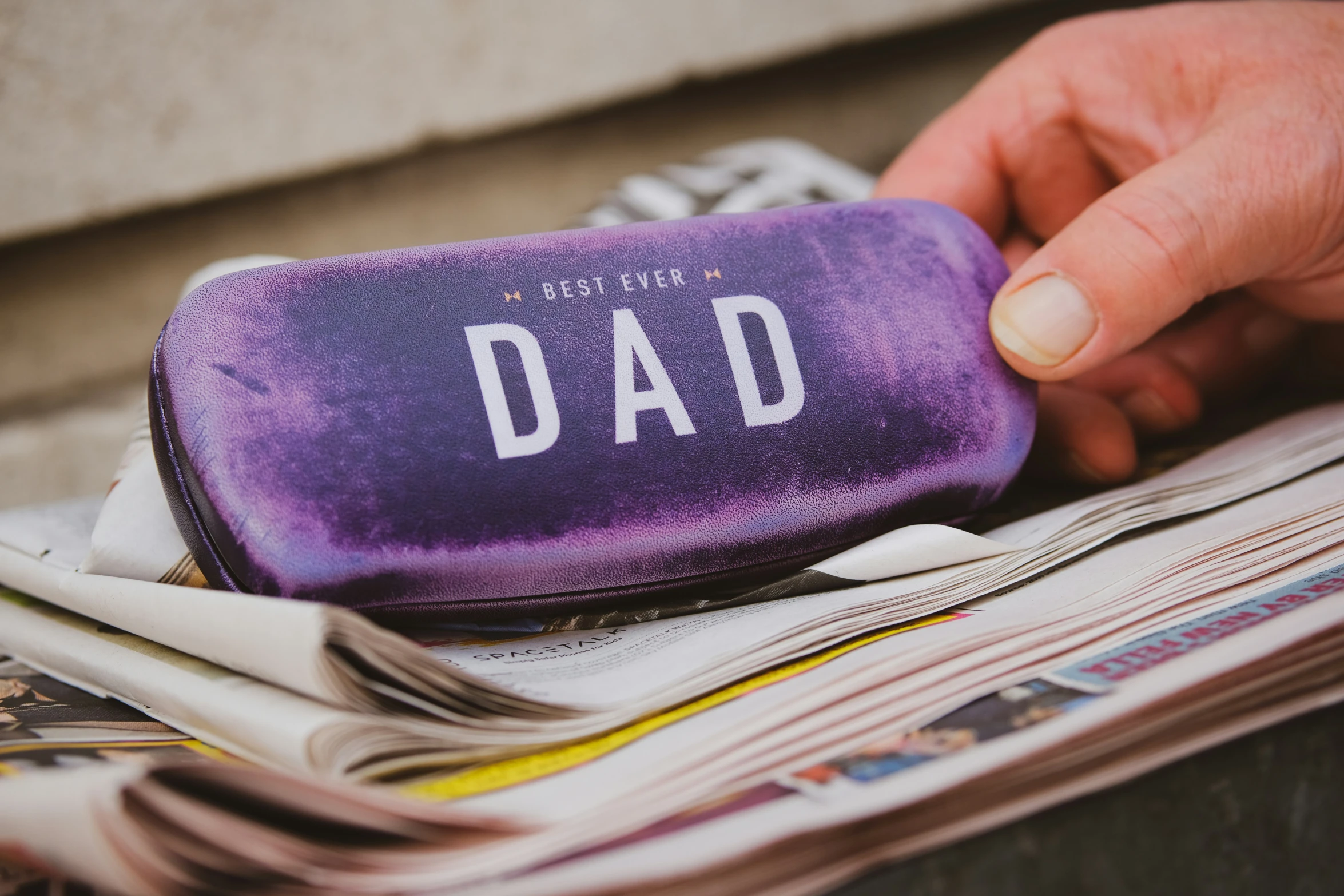 a purple travel case with white letters and some newspaper