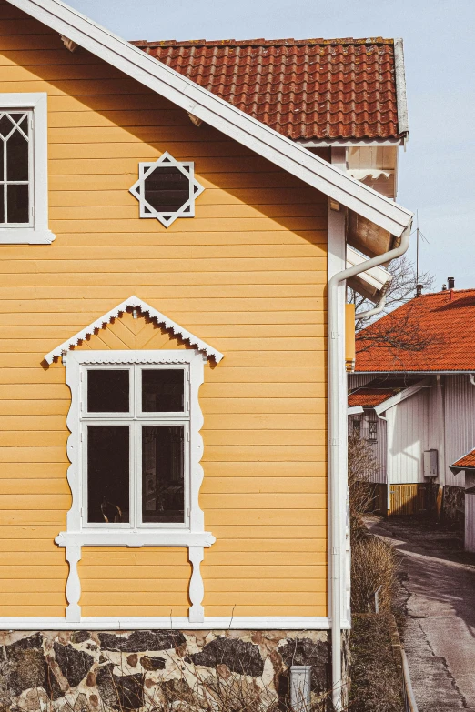 a house with red roof shingles sitting on the side of a street