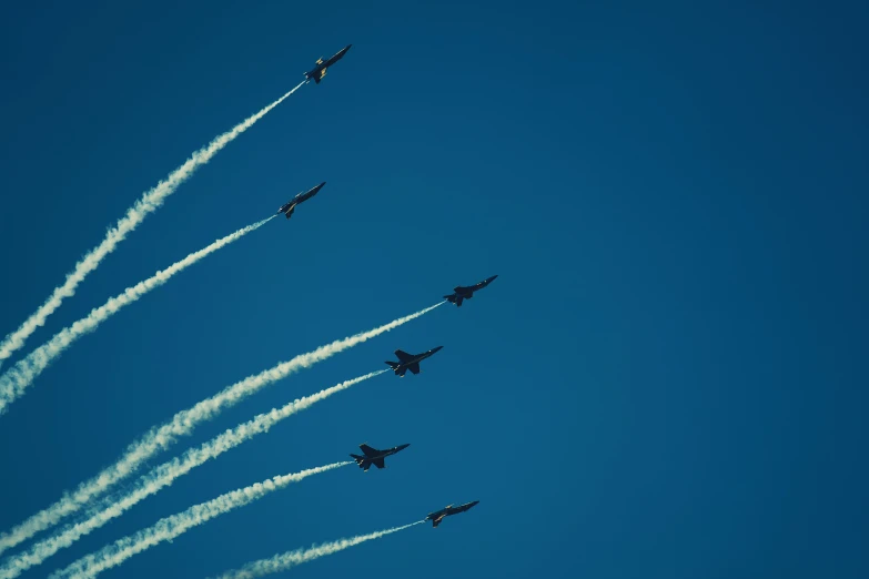 a group of fighter jets flying through the blue sky