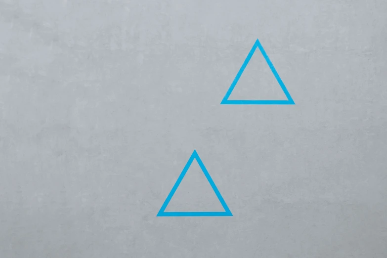 a close up view of a concrete wall with two blue triangle design on it