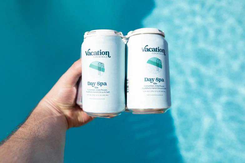 two cans of vacation beer are by a pool