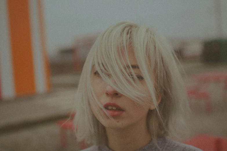 a girl with blond hair sitting in front of a neon sign