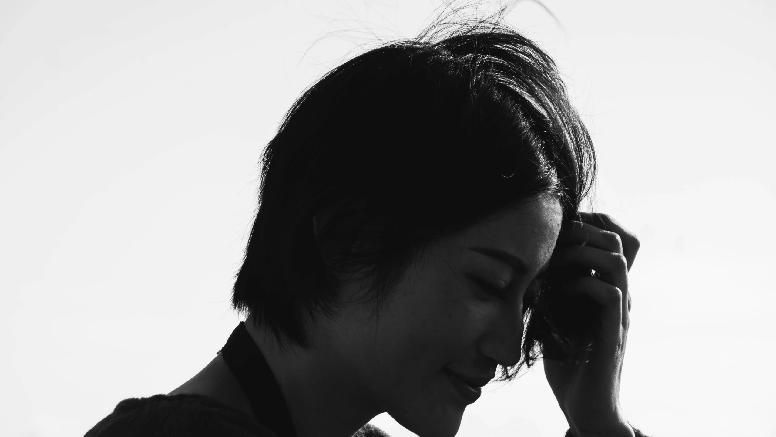 a black and white po of an asian girl covering her ears