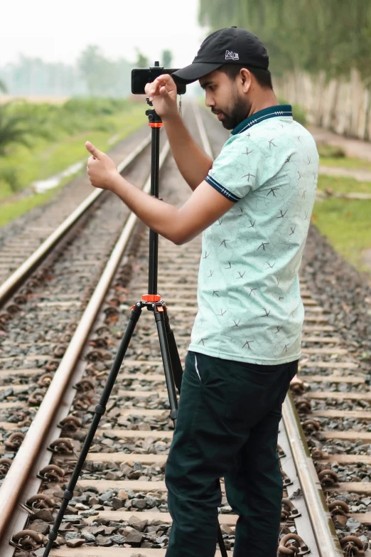 a man standing on top of a train track holding up a camera